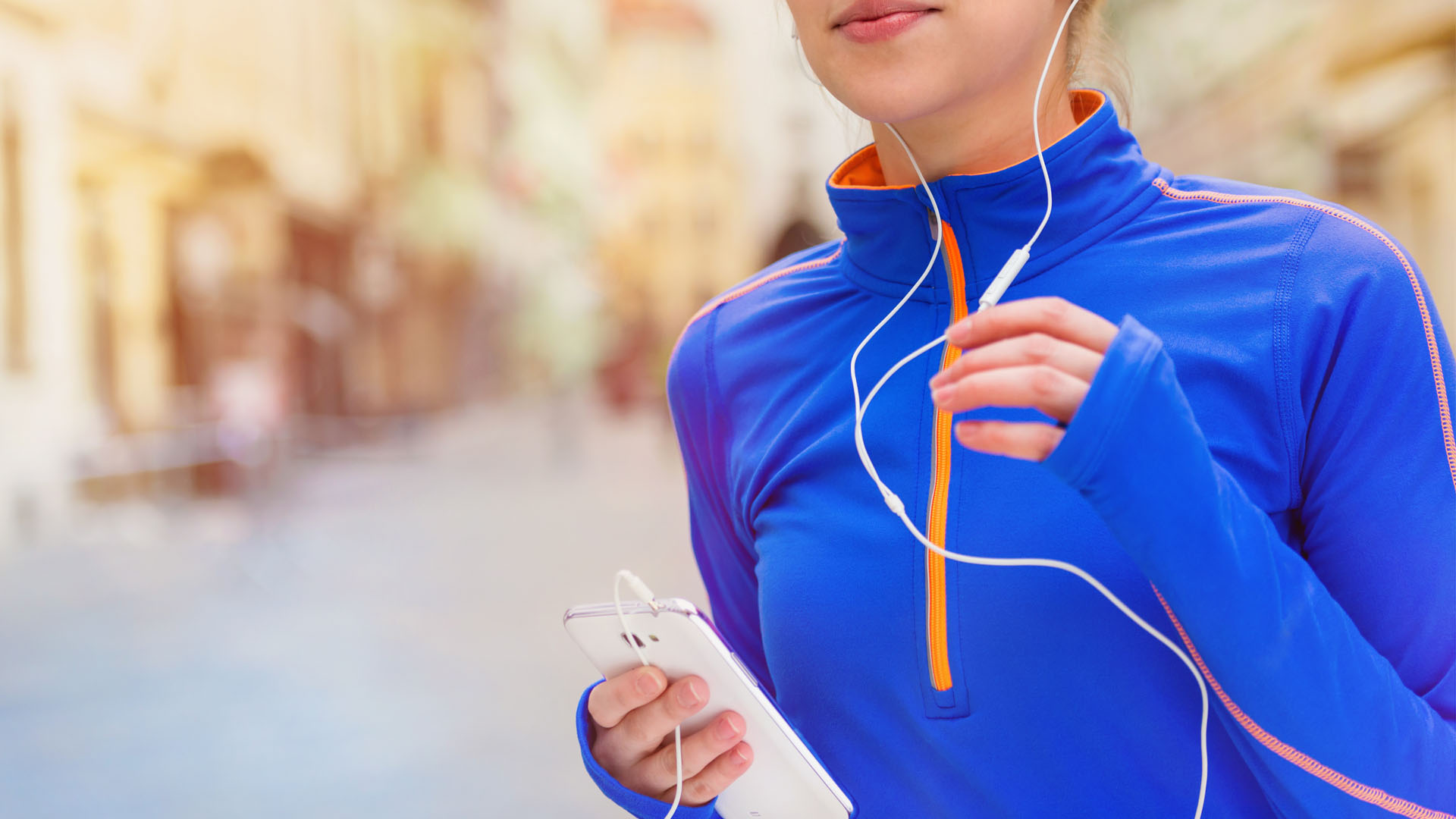 Woman jogging in city streets listening to music