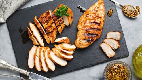 Grilled chicken cut into slices on a slate 
