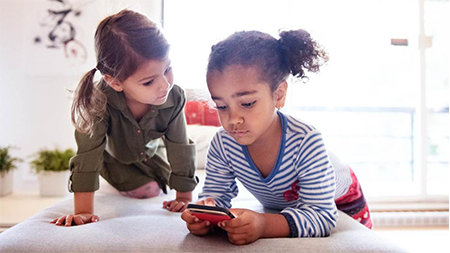 Two young girls looking at a smart phone together