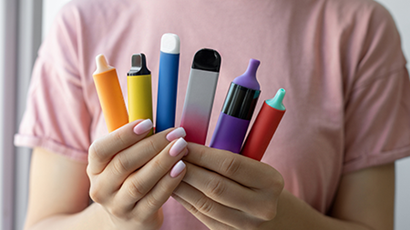 A person holds a variety of vaping products fanned out