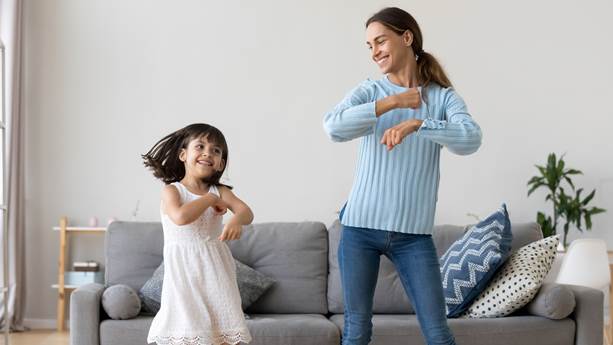 A mother and her daughter dance in their living room 