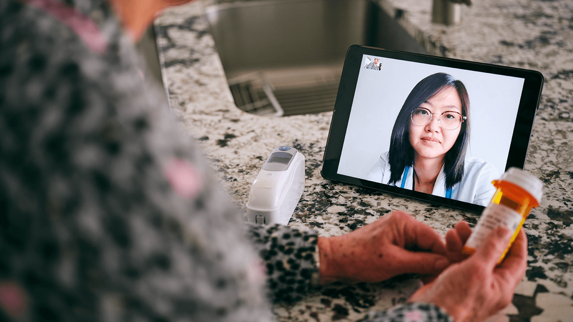 A senior aged woman in her home talking to a doctor online over video conference for a virtual appointment.
