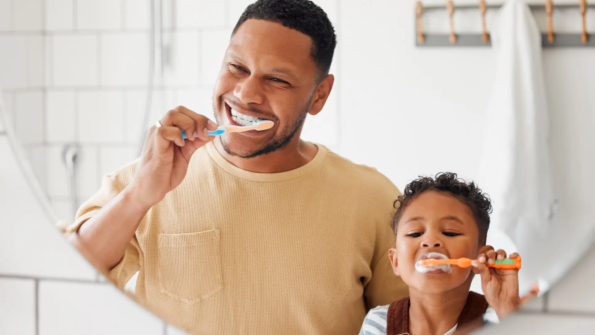 A man and his daughter brush their teeth in front of a mirror.