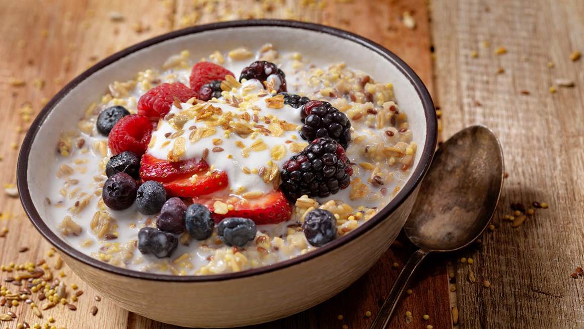 A bowl of oatmeal and berries next to a spoon.