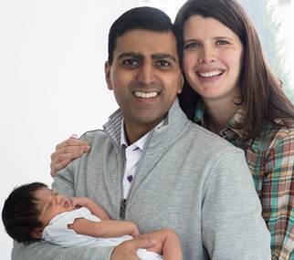 Irfhan Rawji and his wife Christine, stand close together with arms wrapped around their new born baby boy, Zain, while smiling at the camera. 