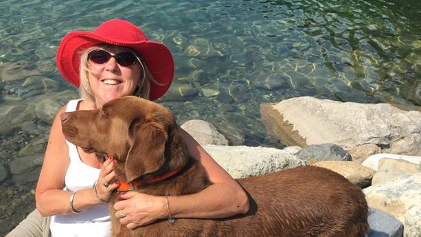Sandra Thornton hugs her dog by a lake.