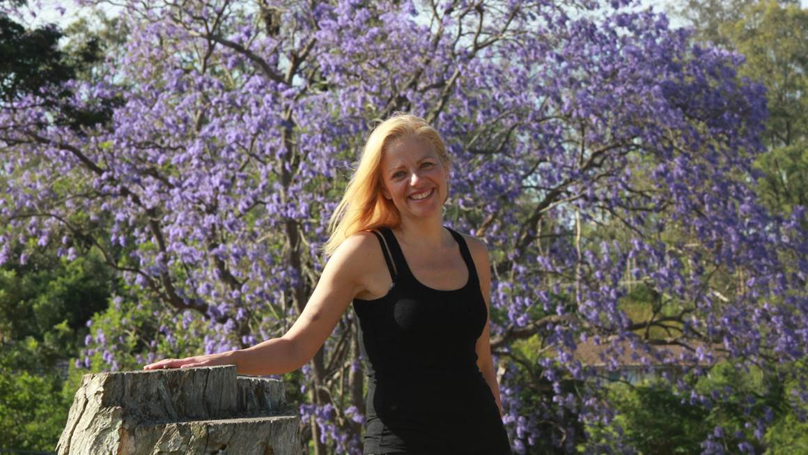Annie Richard smiles in front of a tree with purple flowers