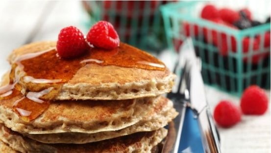 Stack of pancakes on a blue plate topped with raspberries