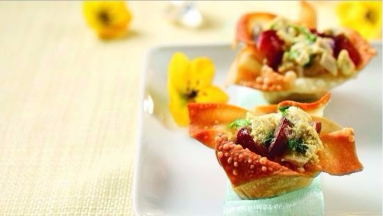 Curried chicken salad in wonton cups sitting on white plate with yellow flowers