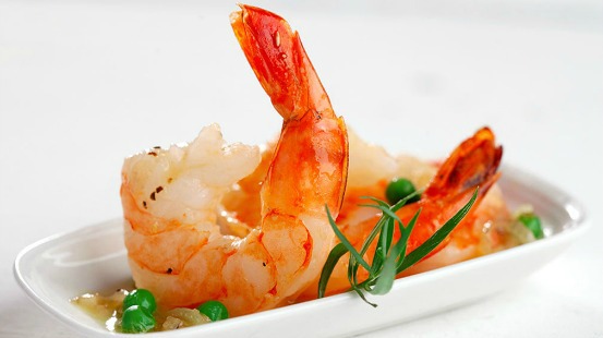 Cooked shrimp and peas served on a white plate