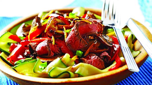 Slices of beef, zucchini ribbons and red peppers in a bowl 