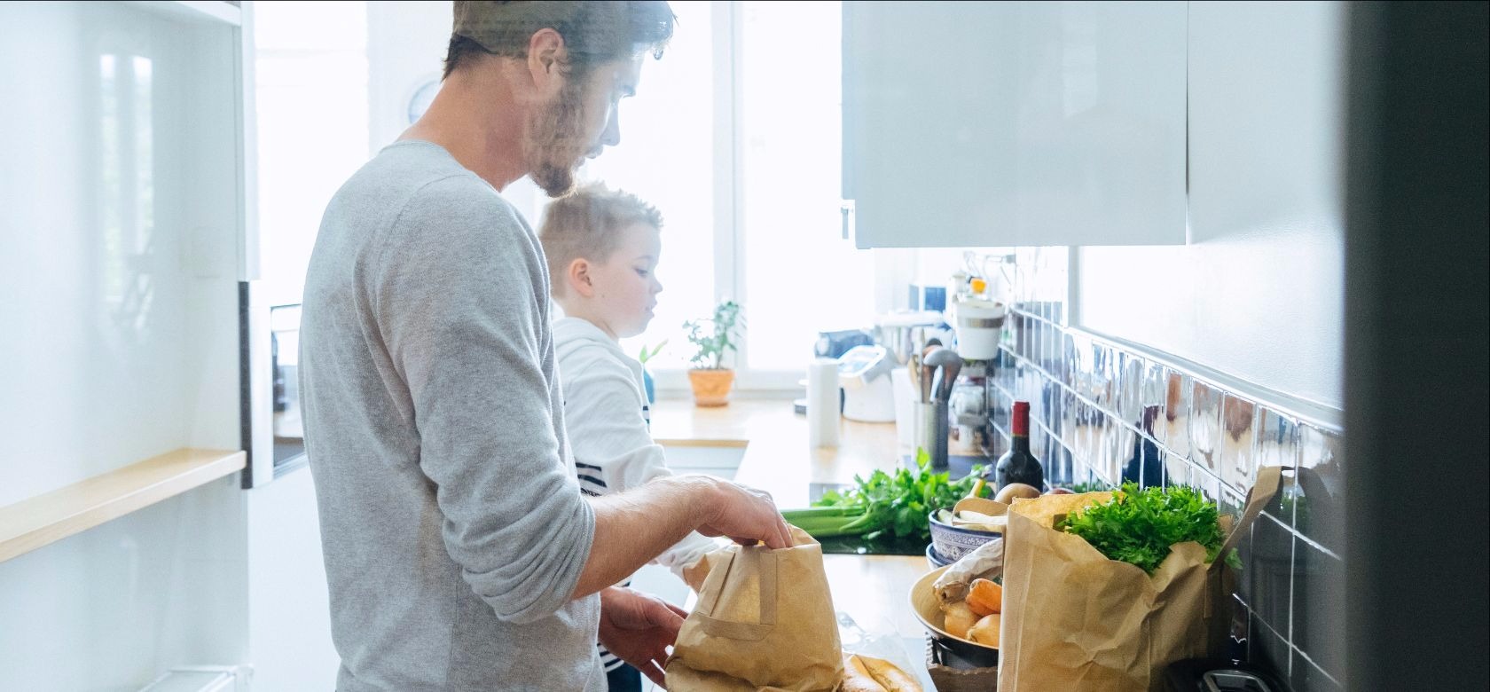 Father and son unpacking groceries in kitchen