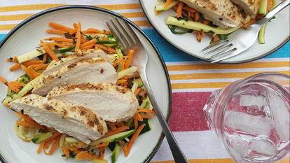Plate of sliced chicken breast with shredded zucchini and carrots 
