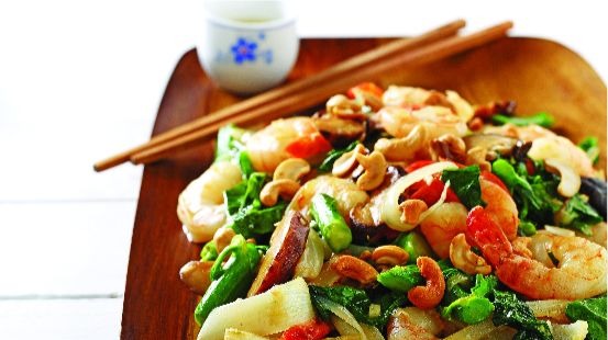 Shimp, bok choy, red peppers, cashews on wooden board with chopsticks