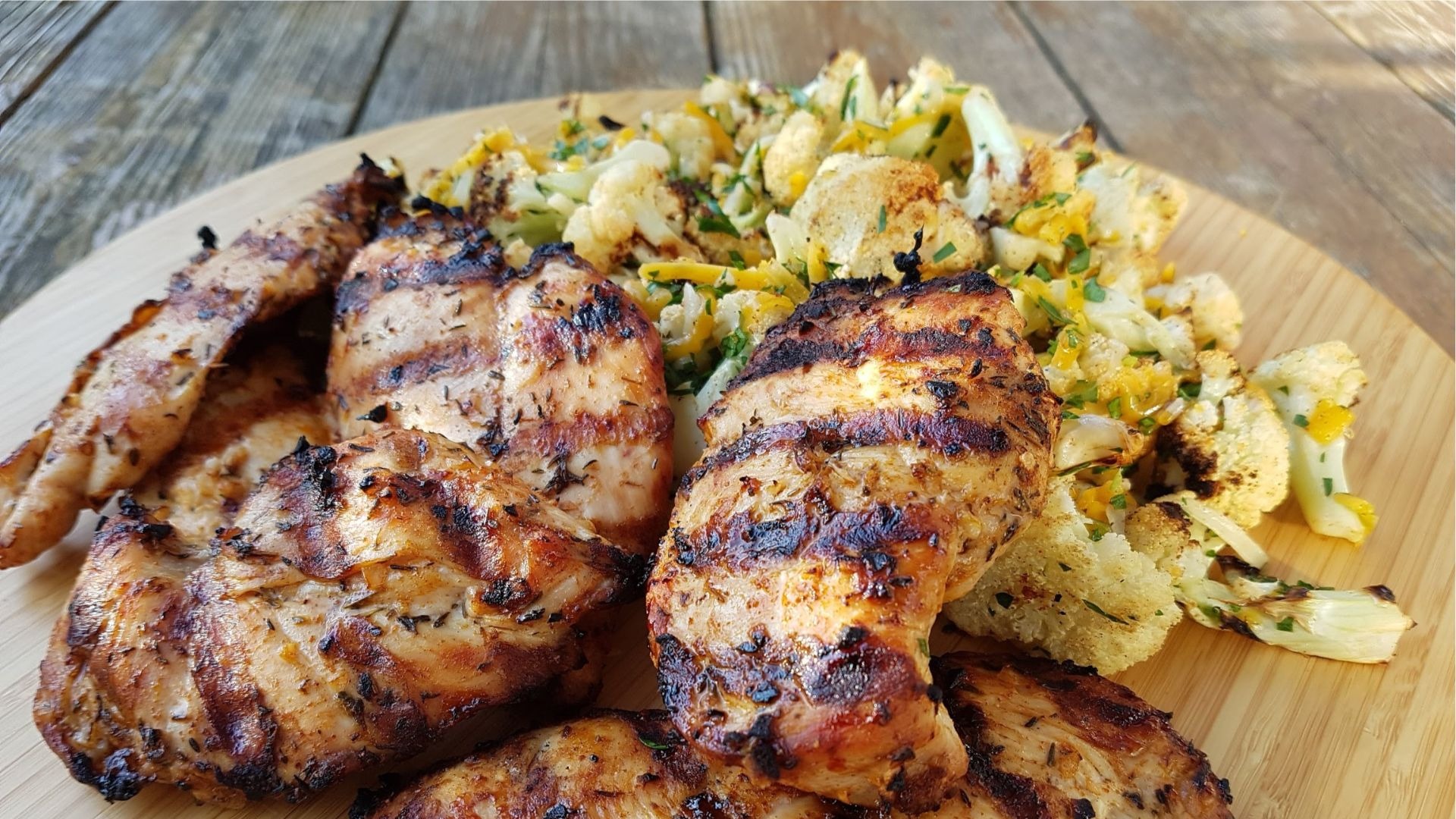 Grilled chicken breasts and cauliflower on wooden board