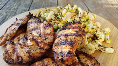 Grilled chicken breasts and cauliflower on wooden board