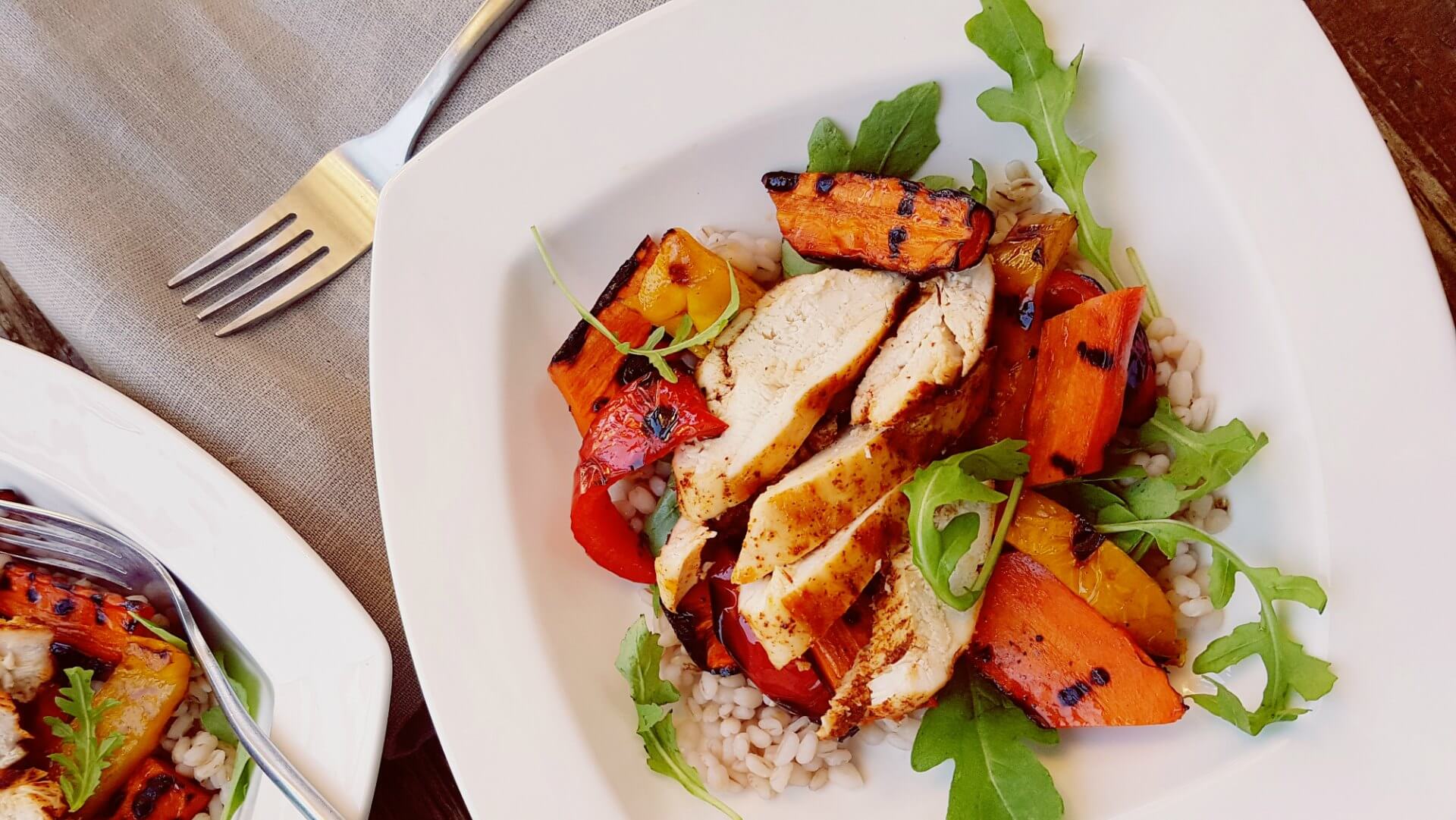 Sliced grilled chicken on barley, arugula, sweet potatoes and red peppers