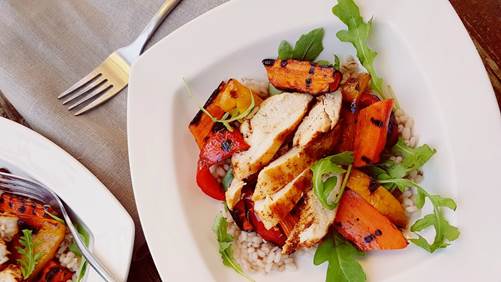 Sliced grilled chicken on barley, arugula, sweet potatoes and red peppers 