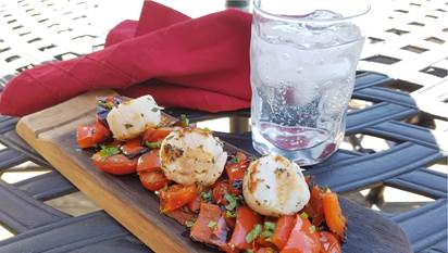 Grilled scallops with roasted tomatoes on wooden plank
