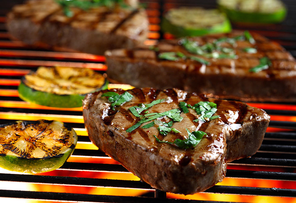 Zucchini and tuna steaks cooking on grill 