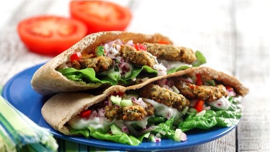 Pita bread filled with falafel, lettuce, tzatziki, tomatoes, onion and cucumber