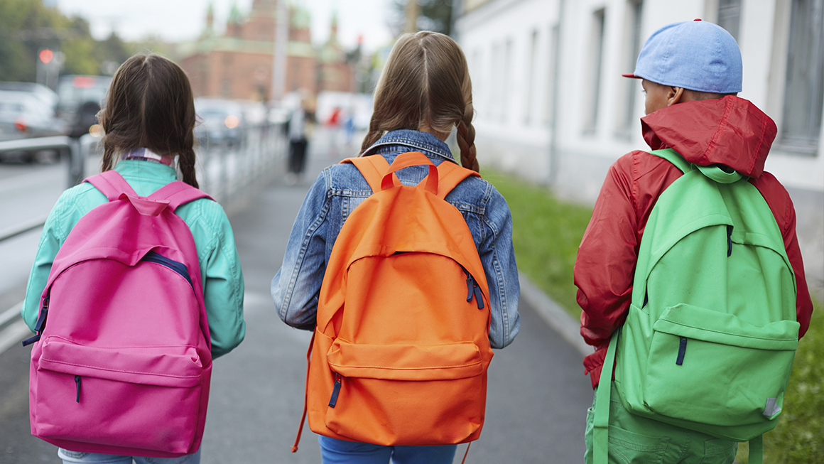  Three children walking to school with backpacks on.
