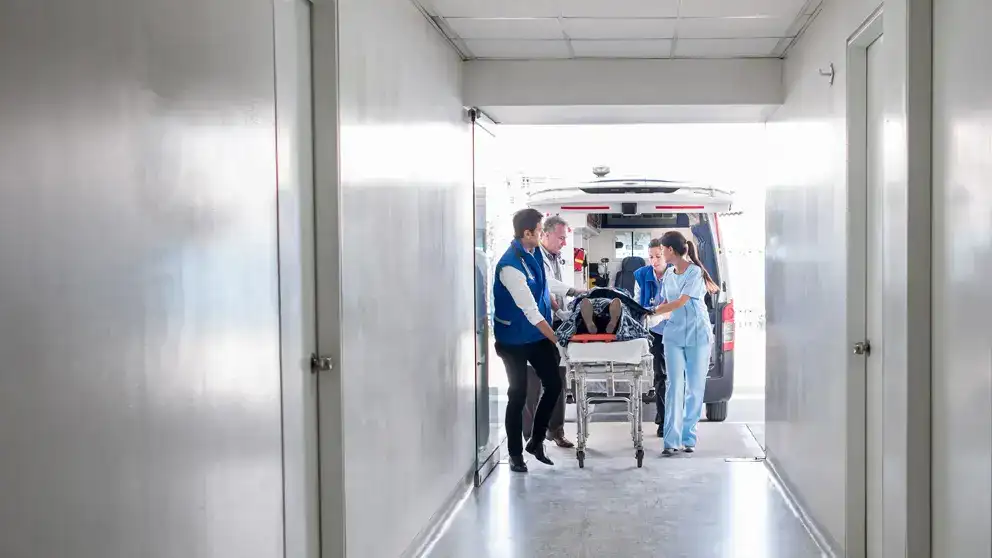 A medical team pushes a patient on stretcher in a hospital.