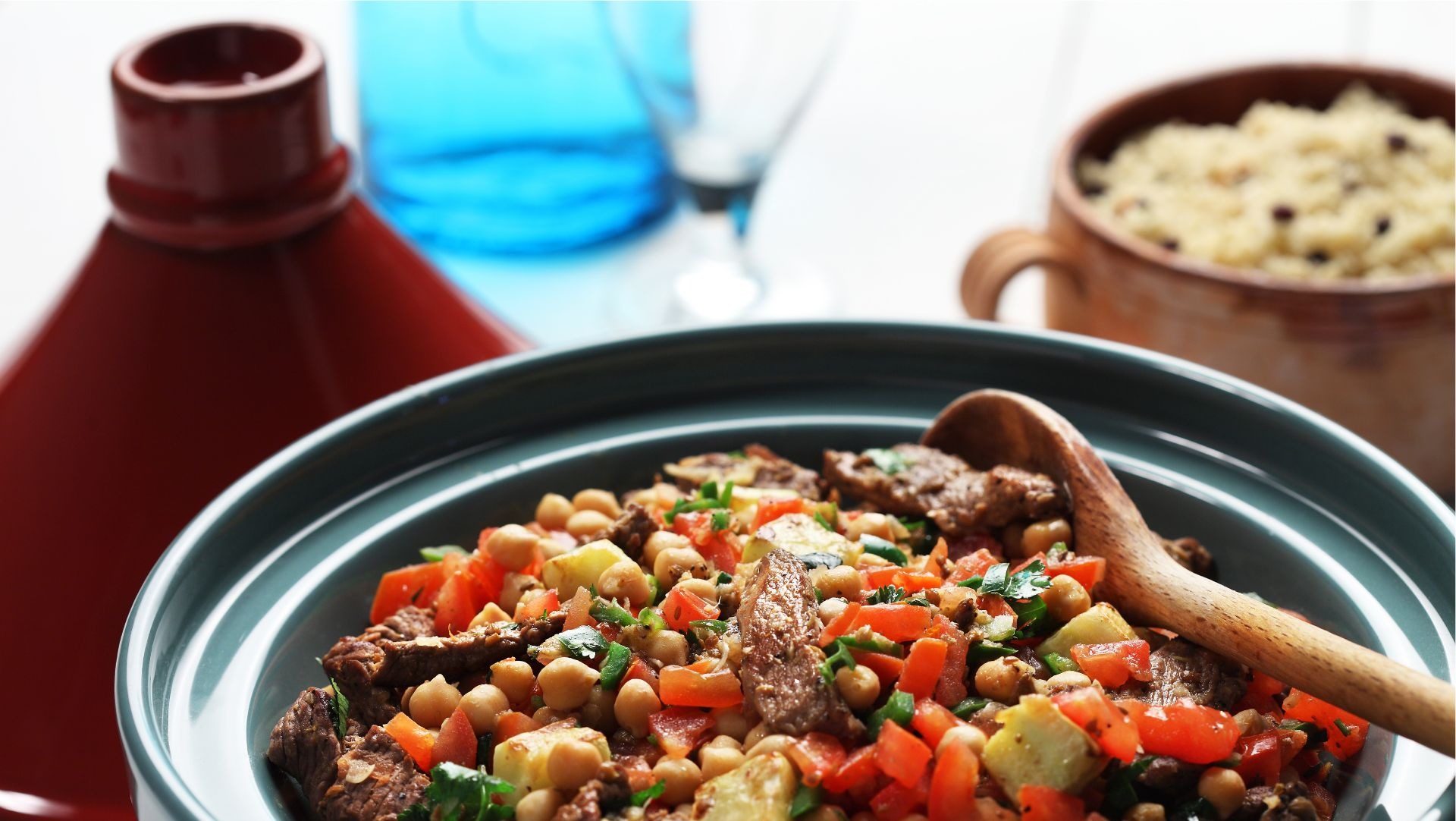 Bowl filled with chickpeas, lamb, chopped tomato, couscous and parsley