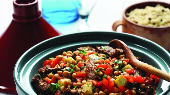 Bowl filled with chickpeas, lamb, chopped tomato, couscous and parsley