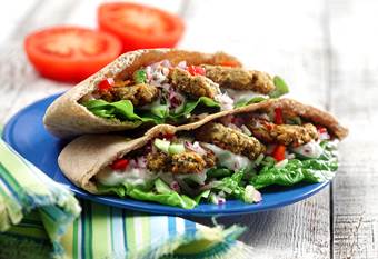 Pita bread filled with falafel, lettuce, tzatziki, tomatoes, onion and cucumber