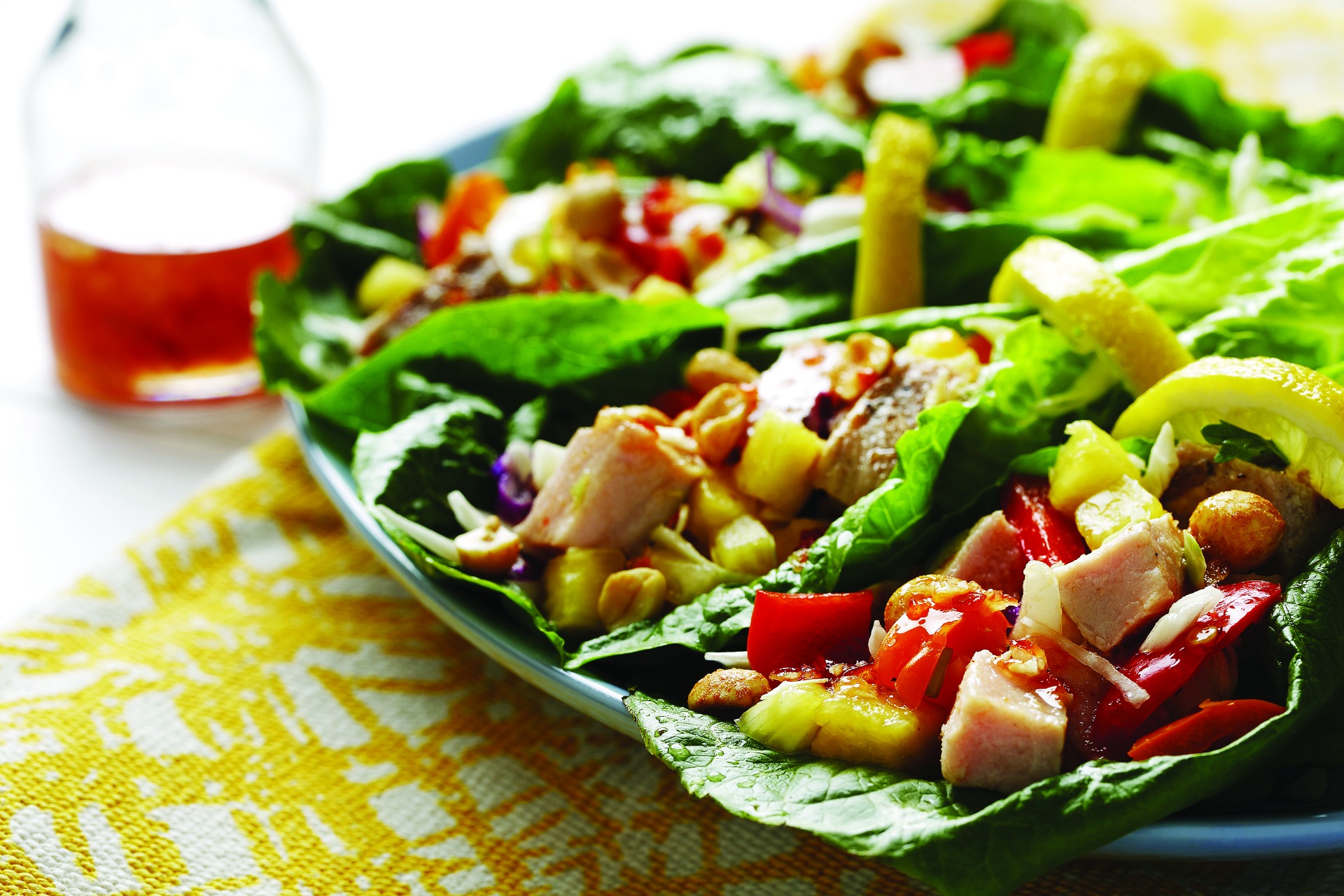 Chopped chicken, roasted red peppers, chopped pineapple and peanuts on a lettuce leaf