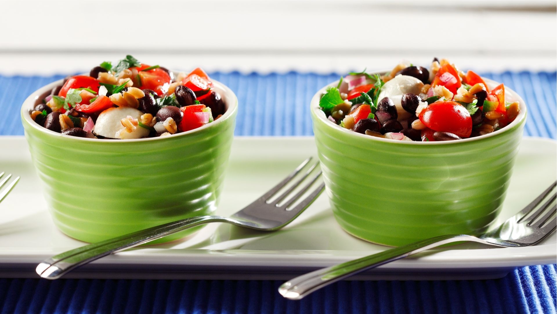 Two ramekins filled with chopped tomato, cilantro, red onions and black beans