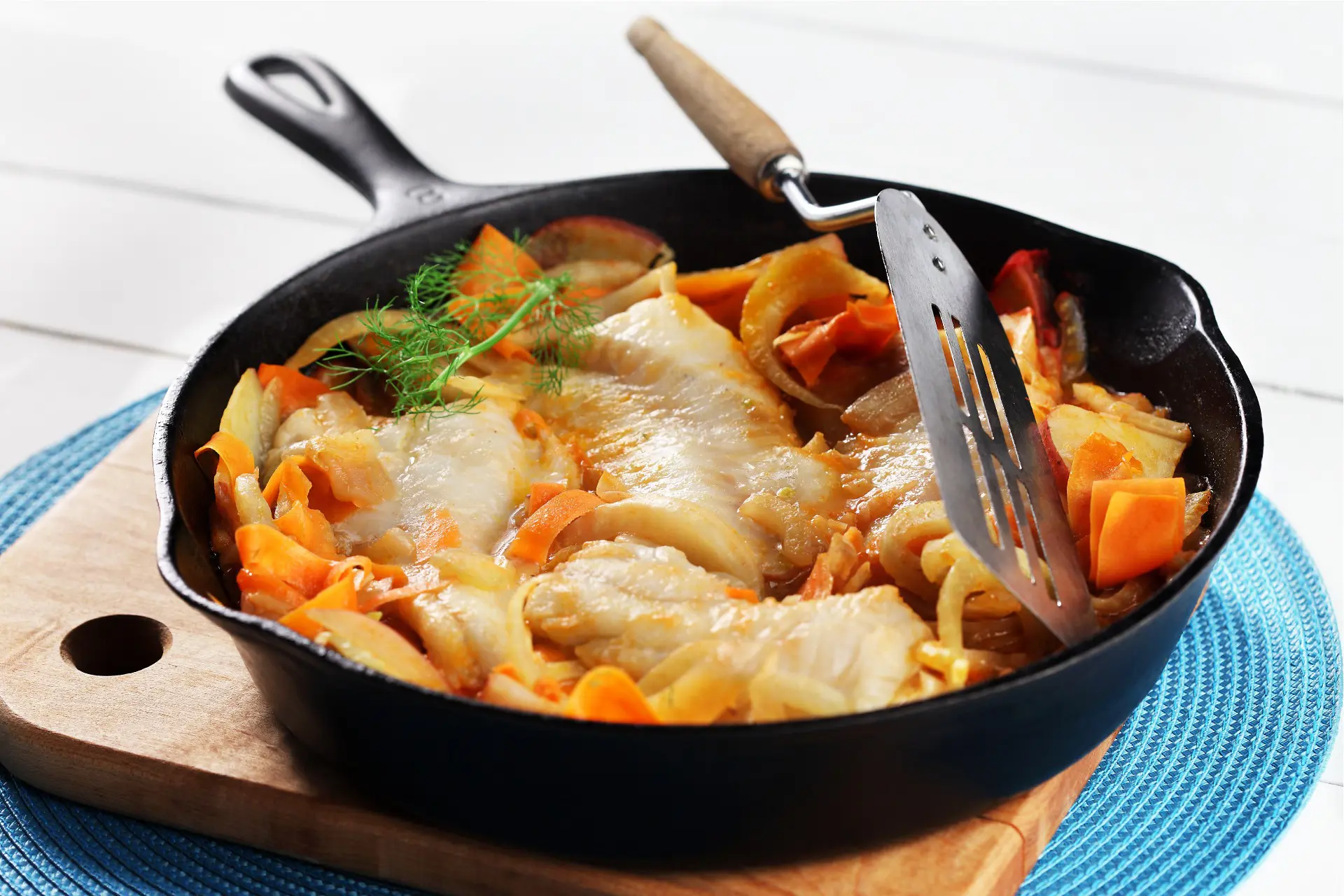 Skillet of cooked cod fillets, fennel potatoes and carrots