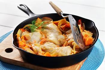 Skillet of cooked cod fillets, fennel potatoes and carrots