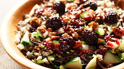 Crunchy wild rice salad with blackberry dressing in a wooden bowl.