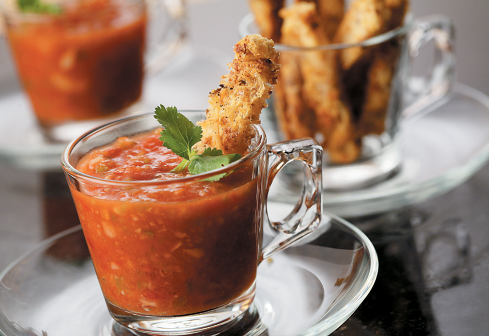 Gazpacho with multigrain croutons in a glass mug.