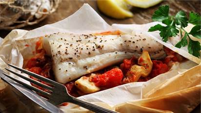 Halibut filet with roasted tomato and artichoke in wax paper packet