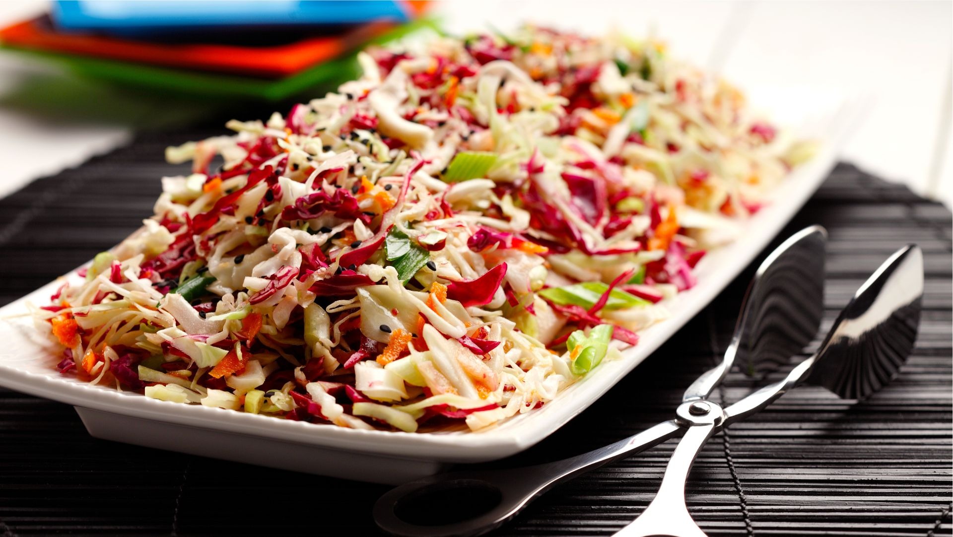 Japanese sesame slaw beside tongs.