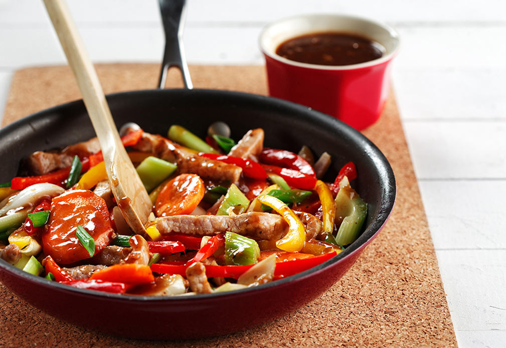 Skillet with sliced pork, peppers, celery, carry and black bean sauce