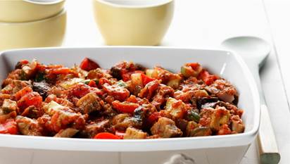 Quick ratatouille in a white baking dish with a serving spoon on the side.