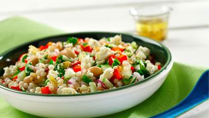 Rosemary-feta pearl couscous salad in a white bowl on a green placemat.
