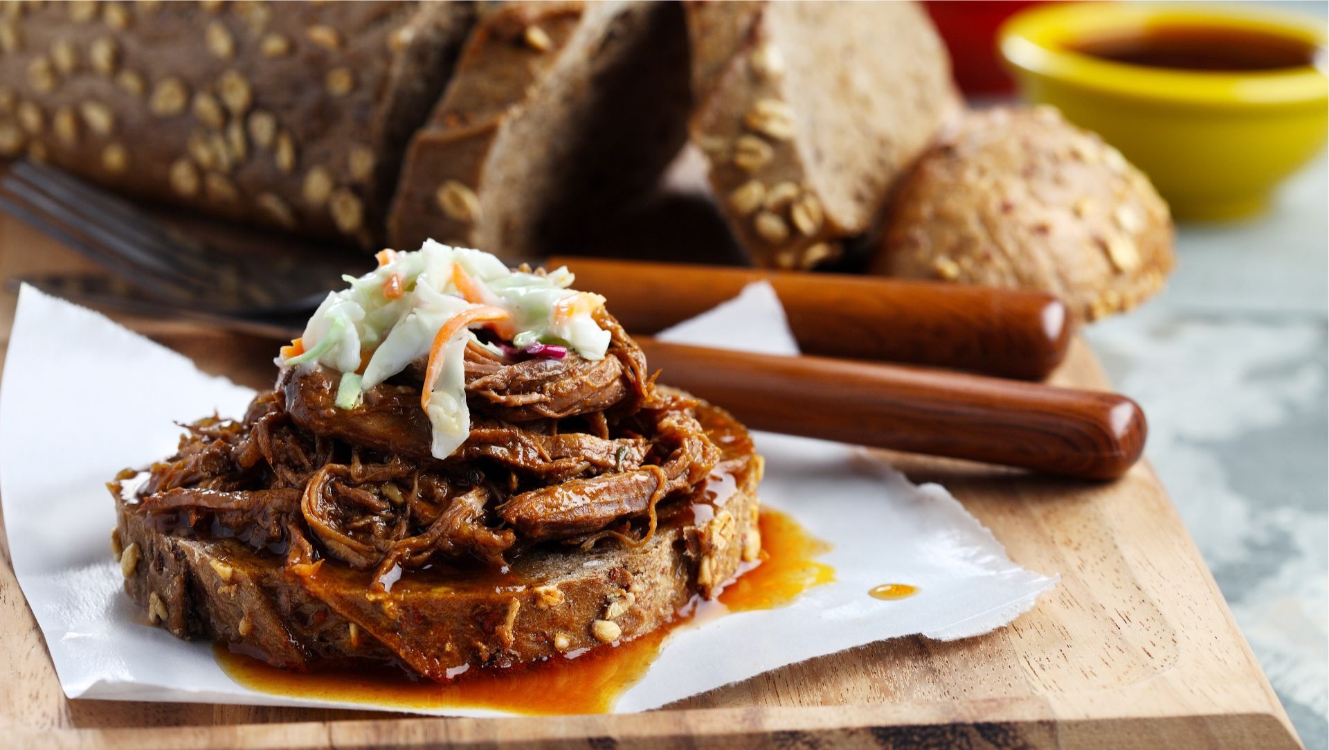 Shredded beef brisket on slice of multigrain bread topped with coleslaw