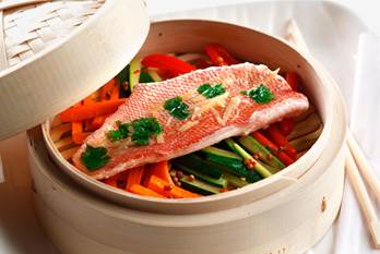 Snapper fillet resting on julliened zucchini, red pepper and carrots in a bamboo steamer