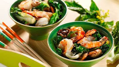 Two bowls filled with shrimp, mushrooms and bok choy on wooden serving tray with chop sticks