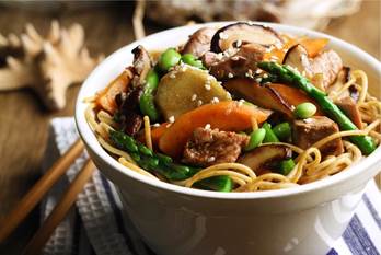 Bowl of vermicelli noodles, edamame, shiitake mushrooms, tuna steak, carrot and asparagus spears