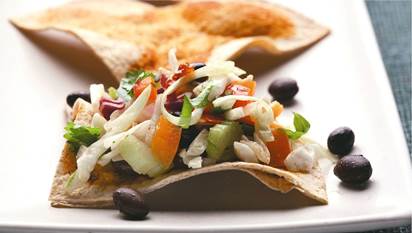 Zesty coleslaw with tortilla triangles on a white plate.