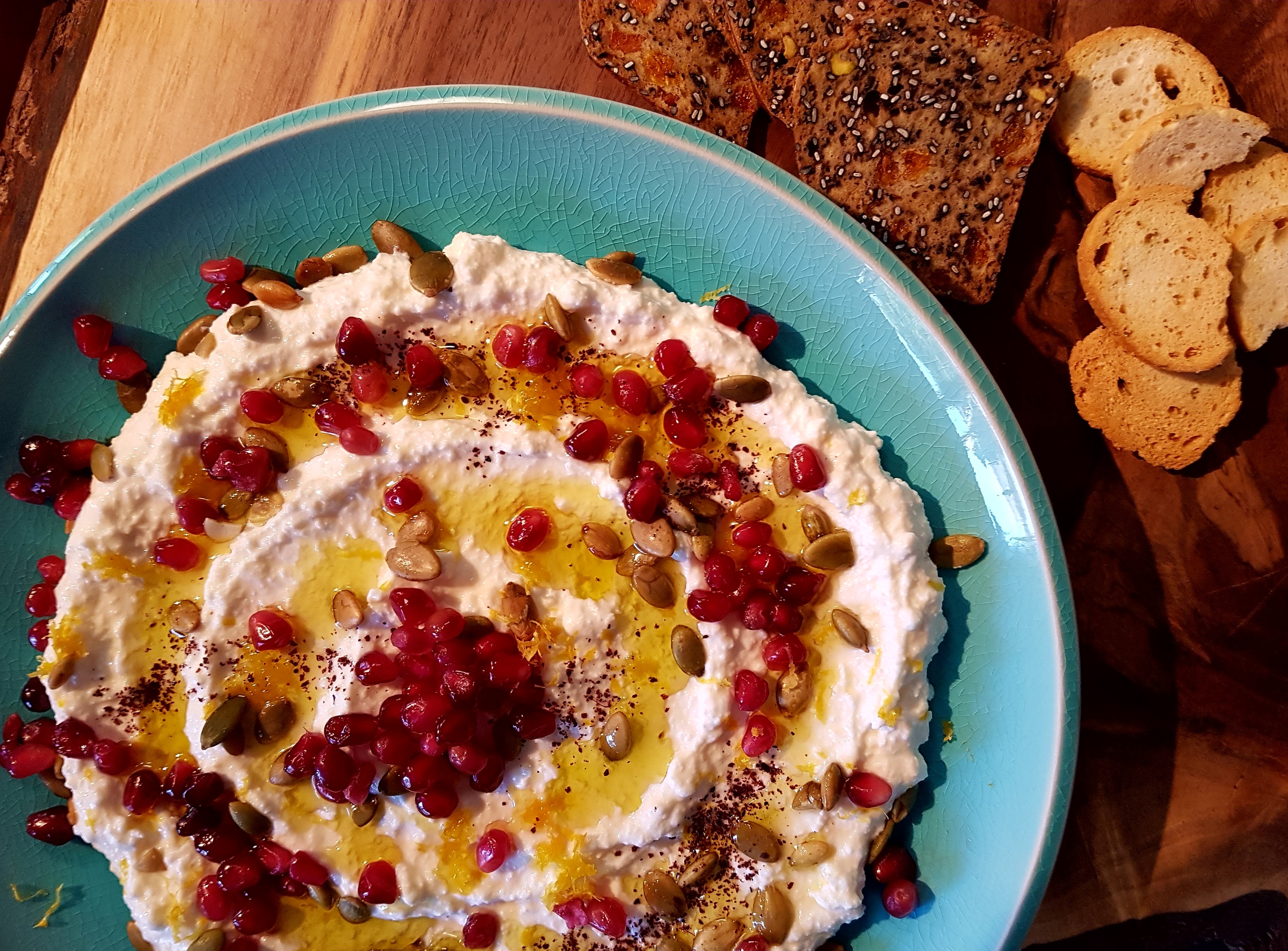 Ricotta and yogurt spread topped with pomegranate, pumpkin seeds and olive oil