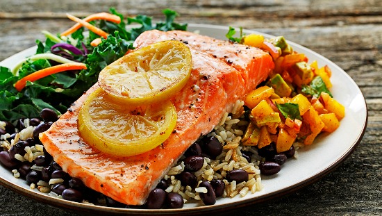 Plate of roasted trout, mango salsa, rice, black beans and green salad  