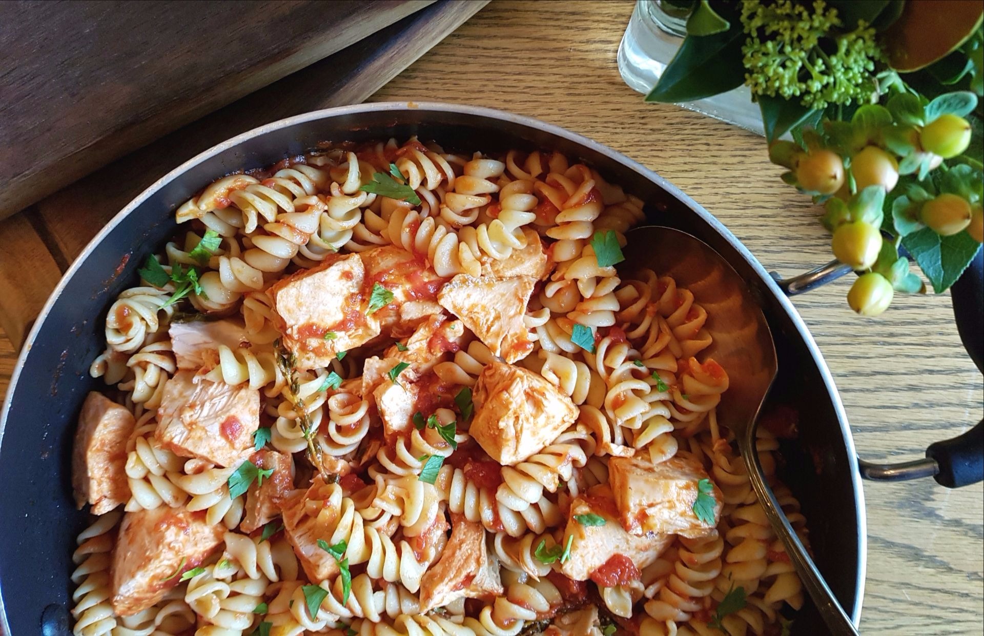 Skillet with cooked salmon, fusilli pasta, tomato sauce and parsley 
