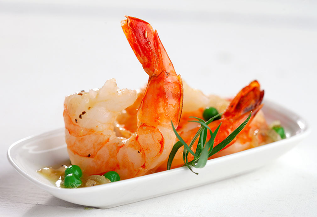 Cooked shrimp and peas served on white plate